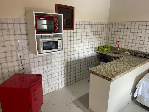 a kitchen with a microwave and a tv on a wall at Pousada Lua Nova Charmosa Pipa in Pipa