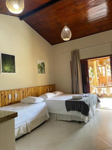 a bedroom with two beds and a large window at Pousada Lua Nova Charmosa Pipa in Pipa