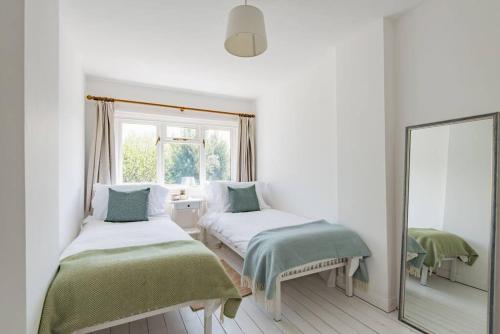 a white room with two beds and a mirror at Peace Cottage in Whitstable