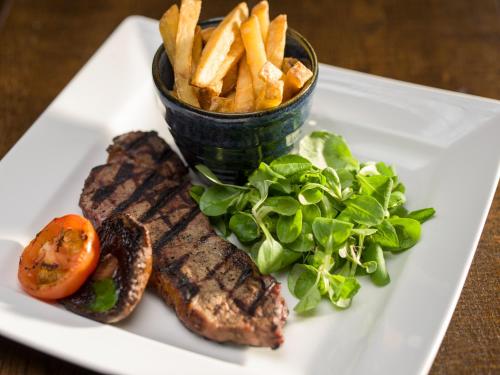 a white plate with steak and french fries and a salad at Holiday Inn Southampton Eastleigh by IHG in Southampton