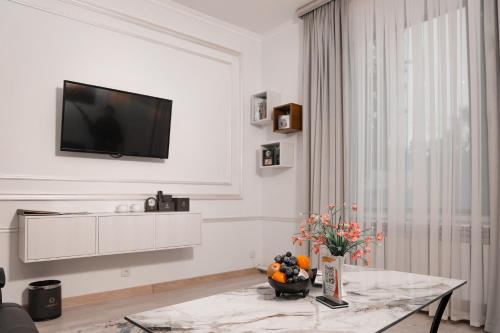 a white living room with a television on a wall at Asmald Palace Hotel in Kokand