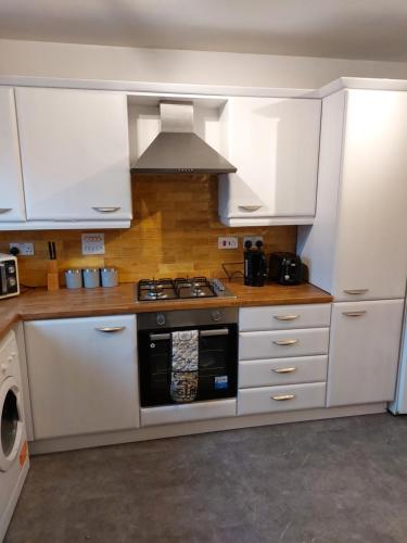 a kitchen with white cabinets and a stove top oven at bankwellstreet in Manchester