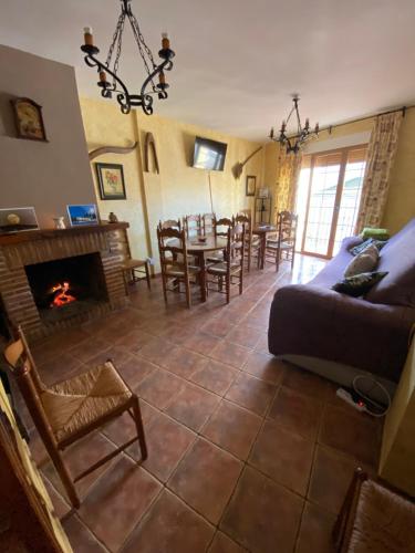 een woonkamer met een open haard en een tafel en stoelen bij Casa Rural Luna del Tiétar in Almendral de la Cañada