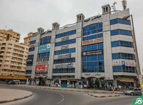 a large building with many windows on a city street at 1 Room in apartment available for rent dating not allowd in Sharjah