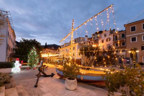 a boat decorated with christmas lights in a city at Hotel Marina - Liburnia in Mošćenička Draga