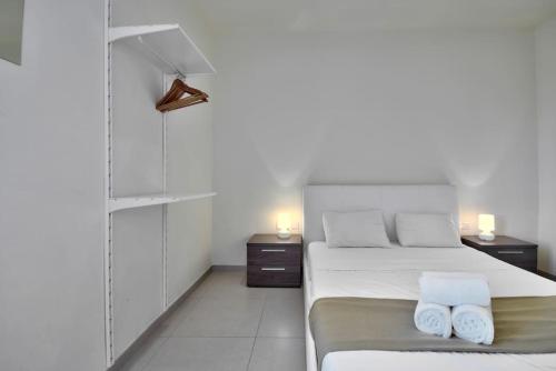 une chambre blanche avec un lit et deux tables de nuit dans l'établissement Lucky Star 103 by Vallettastay, à La Valette