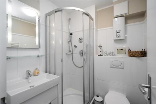 ein weißes Bad mit einer Dusche und einem Waschbecken in der Unterkunft Sylter Rose in Westerland