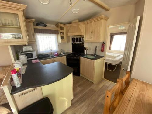 a kitchen with a black counter top and wooden cabinets at Golden Palm Resort - Meadow Lakes 80 - ML80 in Chapel Saint Leonards