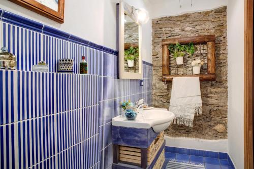 La salle de bains est pourvue de carrelage bleu et blanc et d'un lavabo. dans l'établissement Ca' La Vedescia App Mantaula, à Teglio