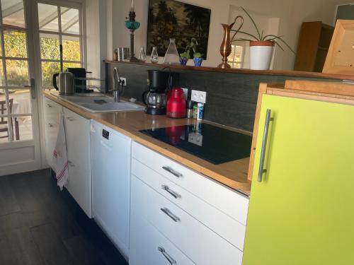 cocina con armarios blancos y nevera amarilla en La Houache Chambres d'Hôtes en Le Pellerin