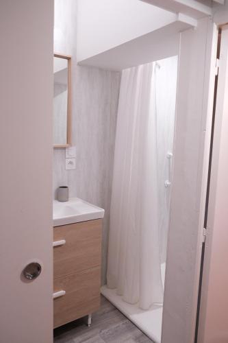 a bathroom with a shower with a white shower curtain at Gîte le petit écolier in Lectoure