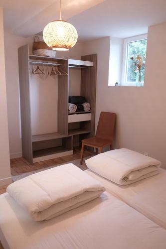 雷克圖爾的住宿－Gîte le petit écolier，一间卧室设有两张床、一把椅子和一个窗户。