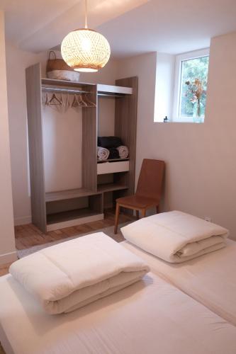 a bedroom with two beds and a chair and a window at Gîte le petit écolier in Lectoure