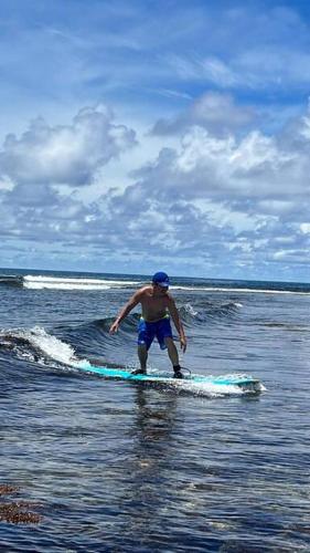 a man standing on a surfboard in the water at Entire Island home with HighSpeed Internet and gated parking in Dapa