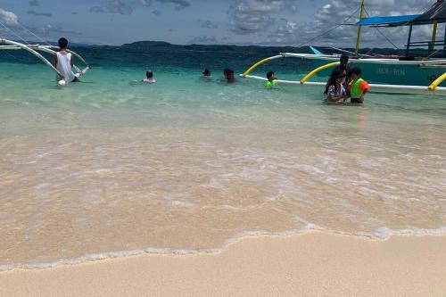 a group of people playing in the water at the beach at Entire Island home with HighSpeed Internet and gated parking in Dapa