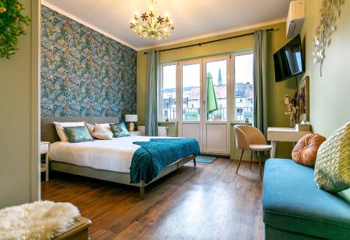 een slaapkamer met een bed, een bank en een raam bij The Newport Lodge - incl Breakfast, 3u Wellness and Ebike in Nieuwpoort