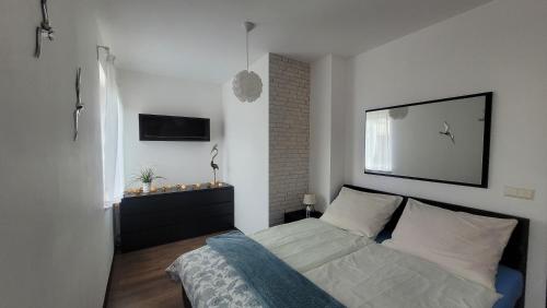 a bedroom with a bed and a television on the wall at Apartament Wyspa, 2 pokoje, parking gratis in Międzywodzie