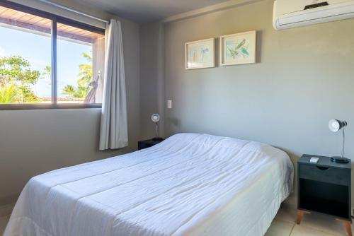 um quarto com uma cama branca e uma janela em Praia Central Porto de Galinhas em Porto de Galinhas