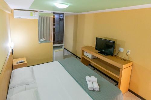 um quarto de hotel com uma cama e uma televisão em Safari Natal Beach Hotel em Natal