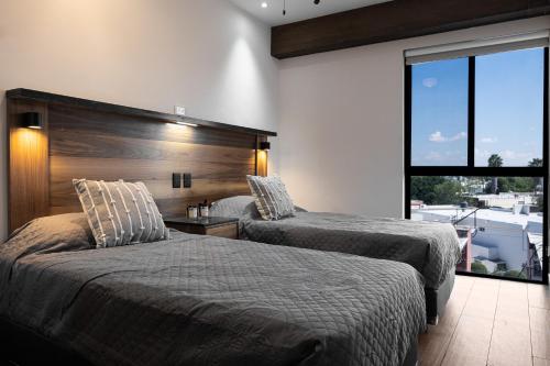 a bedroom with two beds and a large window at Vista al Cerro de La Silla, nuevo con amenidades en Tulancingo 9 in Monterrey