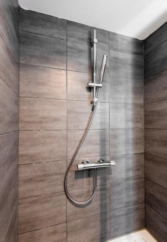 une douche avec un tuyau fixé à un mur dans l'établissement Loc'Ouest 17, à La Rochelle