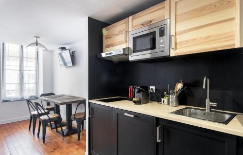 une cuisine avec un évier et une table avec des chaises dans l'établissement Loc'Ouest 17, à La Rochelle