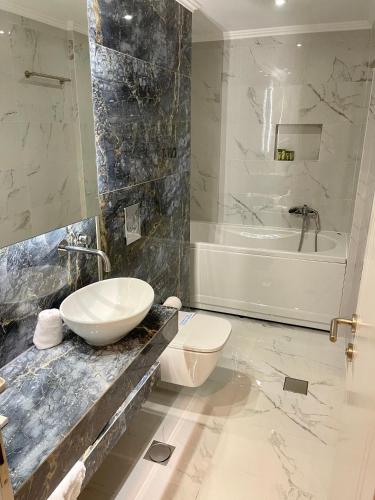 a bathroom with a sink and a toilet and a tub at Aesthesis Arxontiko Luxury Rooms in Mirina