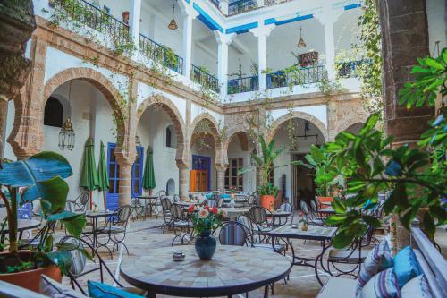 a large room with tables and chairs and plants at Riad Al Madina in Essaouira