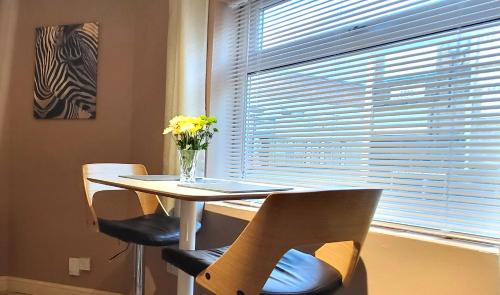 a table with chairs and a vase of flowers on it at Cosy Stays Daybrook in Nottingham
