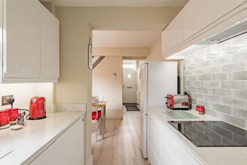 een keuken met witte werkbladen en een witte koelkast bij Middle Deal Cottage in Deal