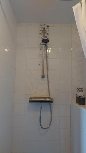 una ducha con una manguera en una pared de azulejos blancos en B en B Sluisje 1818, en Utrecht
