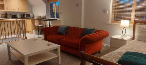 a living room with a red couch and a table at Peaceful self contained Studio in lovely garden. in Hinckley