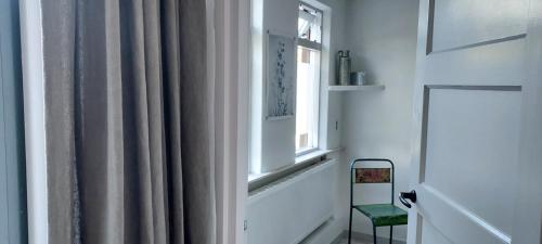 a room with a window and a chair next to a curtain at B en B Sluisje 1818 in Utrecht