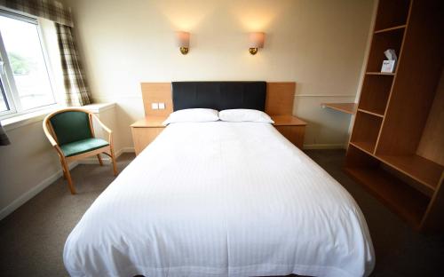 a bedroom with a white bed and a chair at The Caledonian in Portree