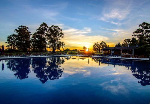 a large pool of water with a sunset in the background at Carmelo Resort & Spa in Carmelo