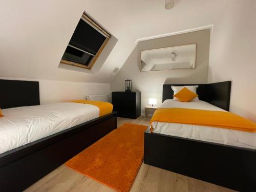 um quarto com 2 camas com lençóis laranja e branco em Le 6B em Hoenheim