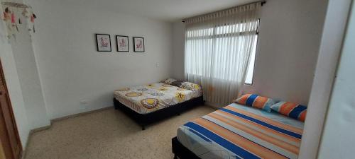 a bedroom with two beds and a window at Apartamento Sector Colores - Estadio in Medellín