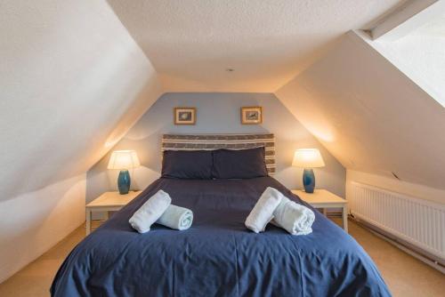 a bedroom with a blue bed with two lamps at Lighthouse Cottage in Deal
