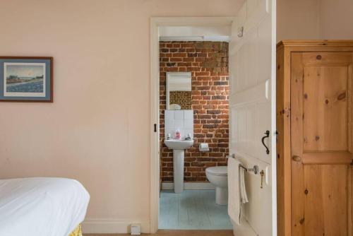 a bedroom with a bathroom with a brick wall at Lighthouse Cottage in Deal