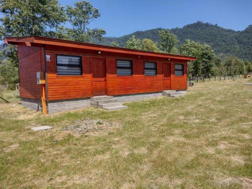 a small wooden cabin in a field of grass at Complejo Turístico Quintuman in Choshuenco