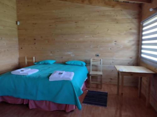 a bedroom with a bed and a wooden wall at Complejo Turístico Quintuman in Choshuenco