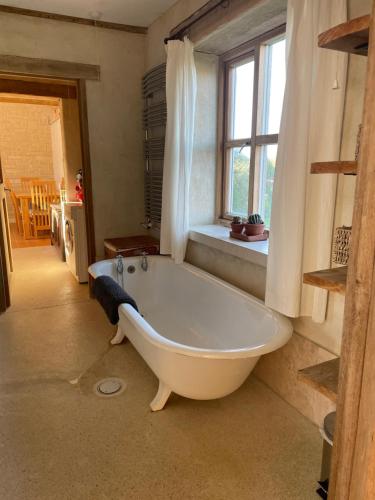 una gran bañera blanca en una habitación con ventana en Shortlake Cottage, en Osmington