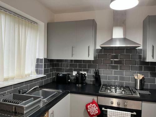 a kitchen with a sink and a stove top oven at Woolfall House in Roby