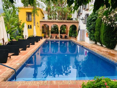 a swimming pool with chairs next to a building at Lovely studio in Marbella close to Puente Romano in Marbella