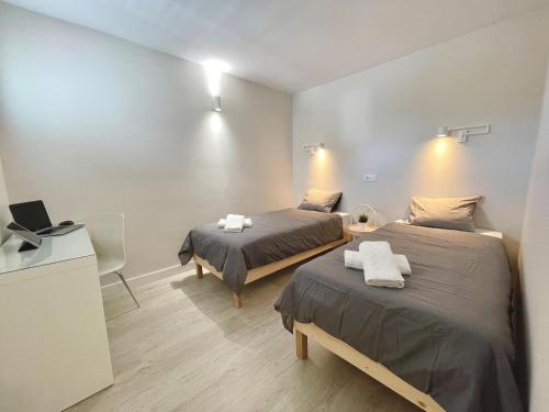 um quarto com duas camas e uma escrivaninha com um laptop em Timeless clock Apartment em San Bartolomé