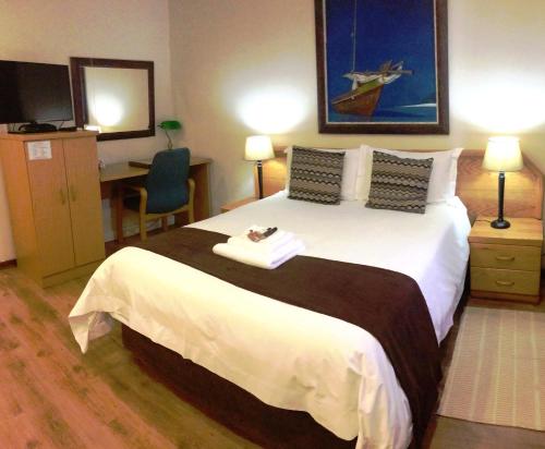 a hotel room with a large bed and a desk at Clubview Guest House in Centurion