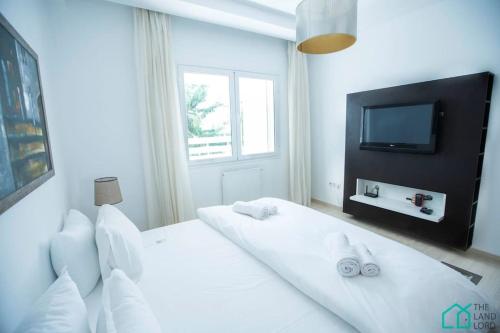 a bedroom with two white beds and a television at Le Premium Central luxueux et très confortable in Sidi Daoud