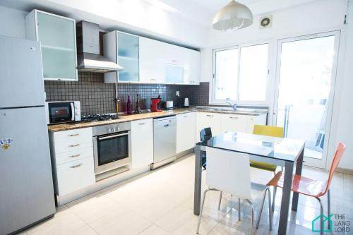 a kitchen with white cabinets and a table with chairs at Le Premium Central luxueux et très confortable in Sidi Daoud