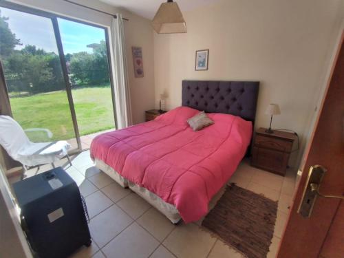 1 dormitorio con 1 cama con manta rosa y ventana en Casa en Marbella, en Maitencillo