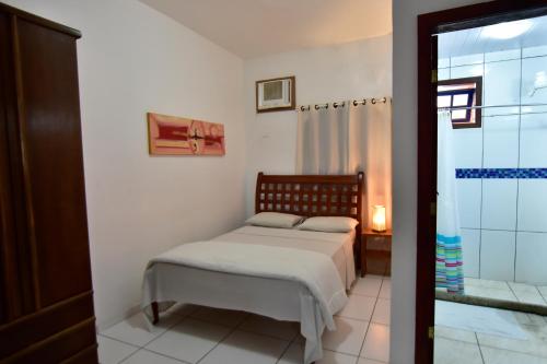 a small bedroom with a bed and a shower at Estalagem 11 Suites in Arraial do Cabo